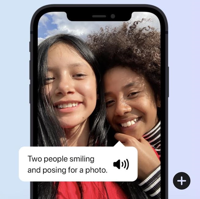 A phone showing a photo of two women smiling and voiceover describing the photo
