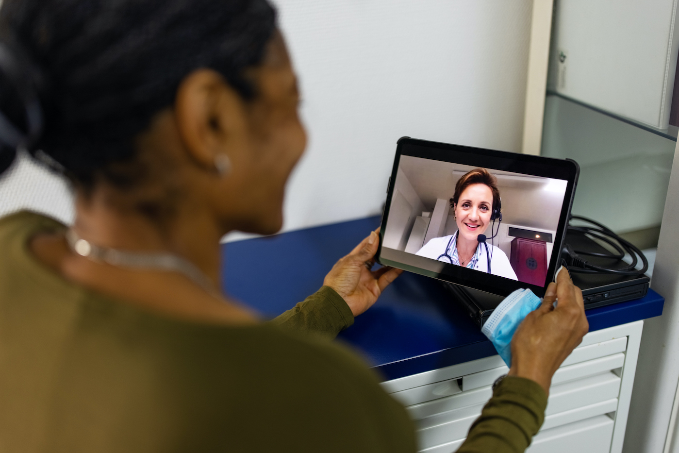 Woman having a medicine video conferencing with her doctor using digital tablet. Senior woman on a video call with a doctor using her tablet computer at home.